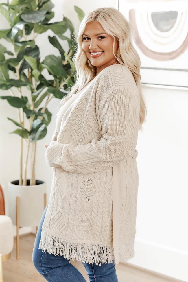 Definitely not having any doubts this long sleeved cardigan in a beige cable knit with a fringed hem is comfy and slouchy. This cardigan looks fantastic over a bodysuit and with jeans.