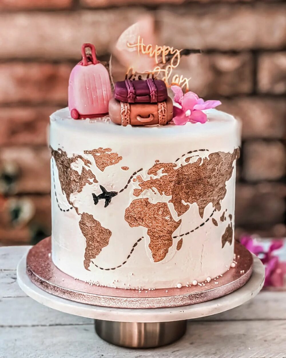 The pink and copper cake is perfect for celebrating a birthday sending well wishes on a new adventure or commemorating a significant travel related achie
